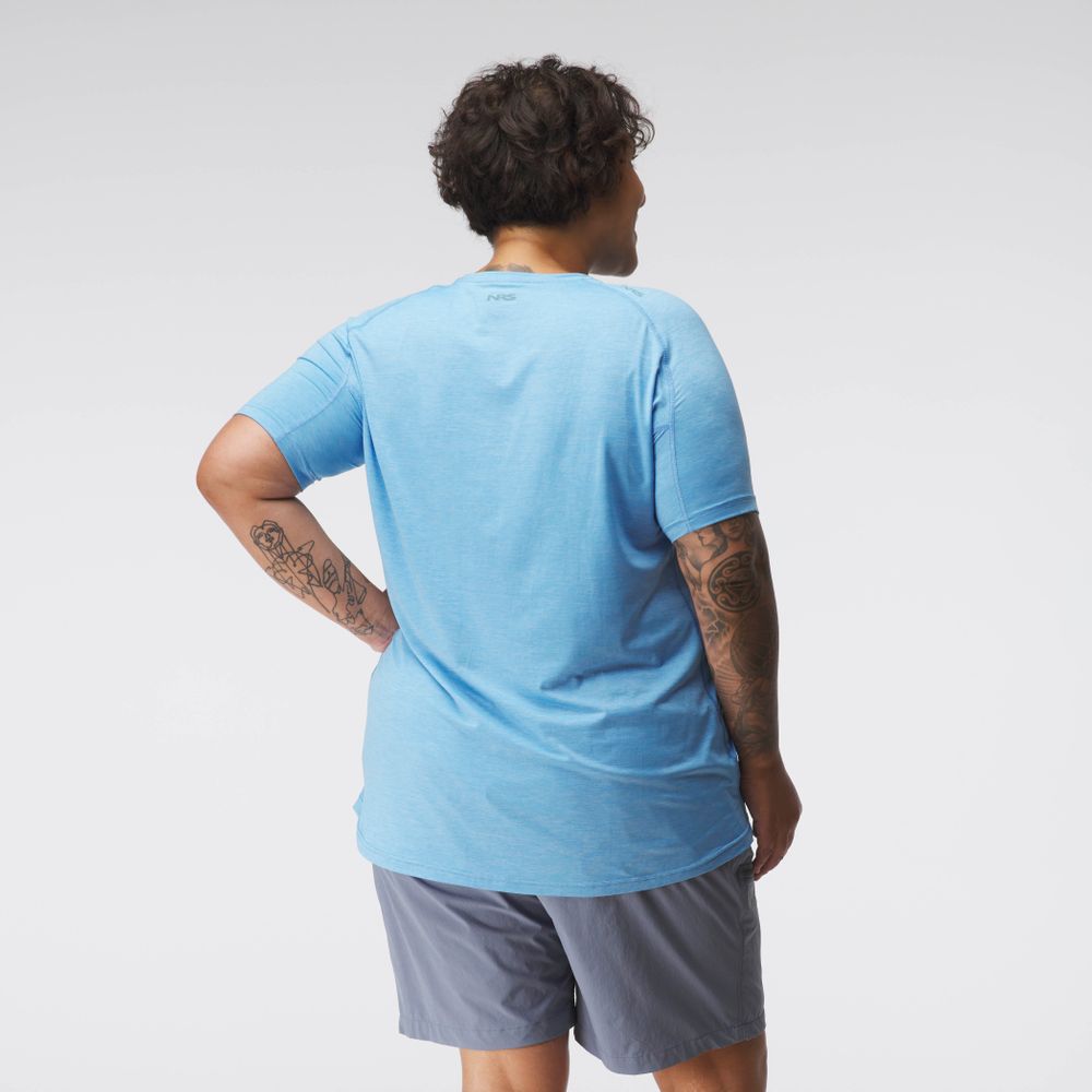 An individual in an NRS Silkweight Short Sleeve Shirt - Women's, paired with gray shorts and showcasing eye-catching arm tattoos, faces away from the camera. The moisture-wicking fabric ensures comfort during any activity.