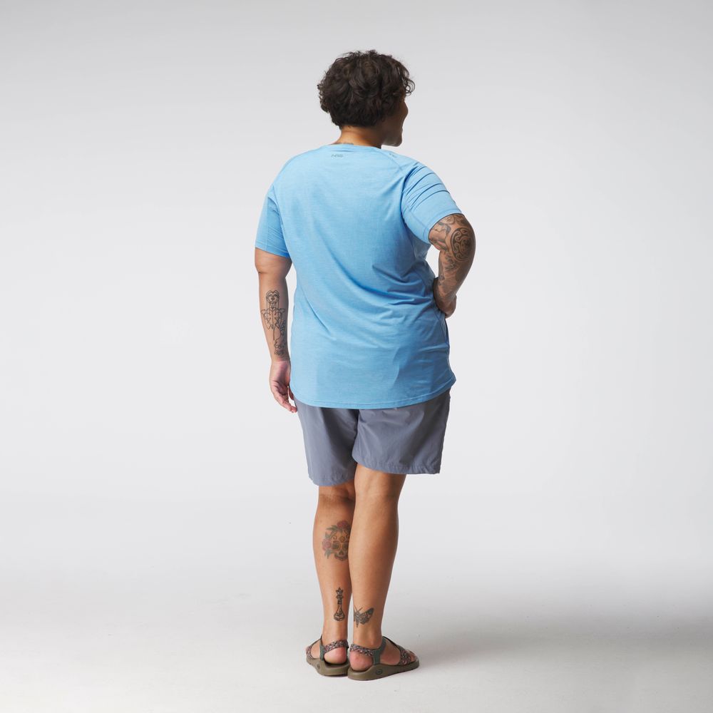 A person with short hair wears an NRS Silkweight Short Sleeve Shirt in blue and gray shorts, standing in sandals with their back to the camera.