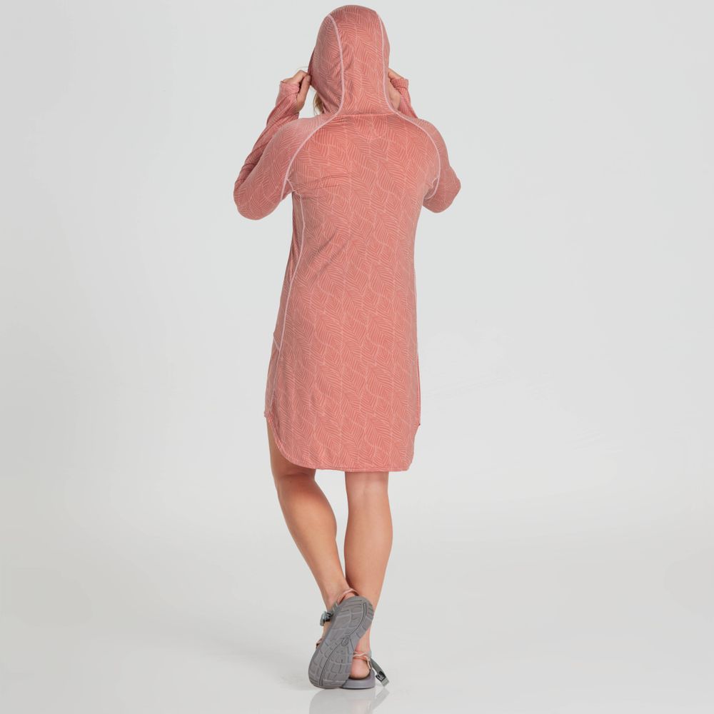 With their back turned, a person adjusts the hood of a pink NRS Silkweight Hoodie Dress, offering comfortable sun protection and crafted from recycled materials for a stylish, sustainable look.