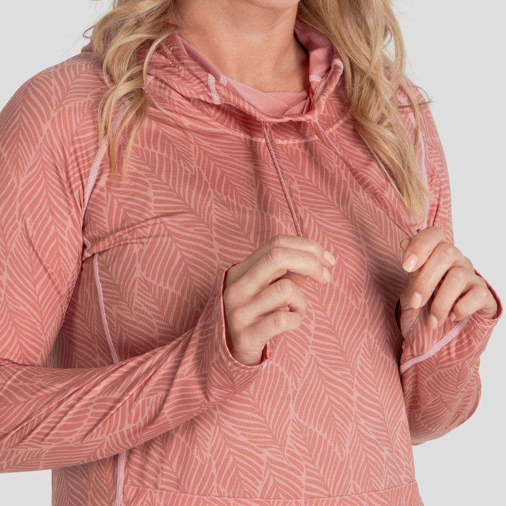 Someone is adjusting the hood strings of their pink, leaf-patterned NRS Silkweight Hoodie Dress, highlighting its elegant design against a neutral background. Crafted with recycled materials, it combines style and sun protection.