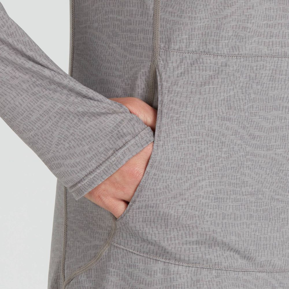 Close-up of a person wearing the NRS Silkweight Hoodie Dress, a long-sleeve gray top with a subtle pattern made from recycled materials, with their right hand tucked into a pocket.