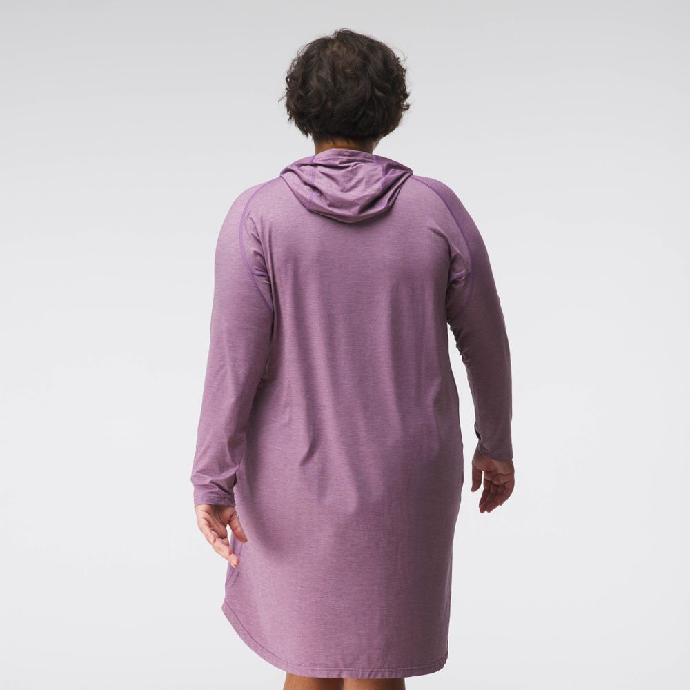 A person with short hair is facing away, wearing the NRS Silkweight Hoodie Dress, a long-sleeved hooded dress in purple made from recycled materials.