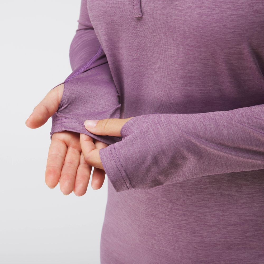 An individual wearing an NRS Silkweight Hoodie Dress, a purple long-sleeve top crafted from recycled material featuring thumb holes, highlights the sleeve details.