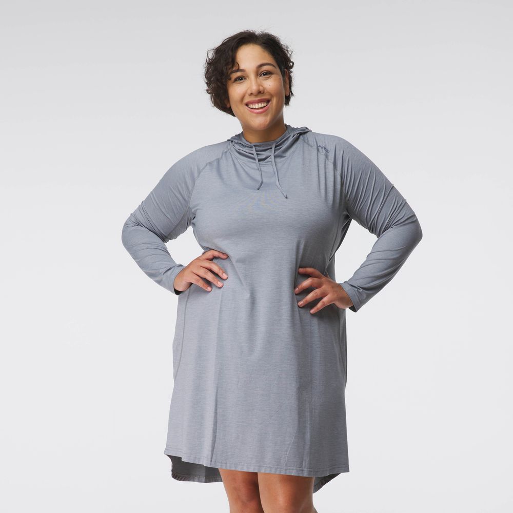 A person stands smiling, wearing the NRS Silkweight Hoodie Dress in light gray, made from recycled materials.