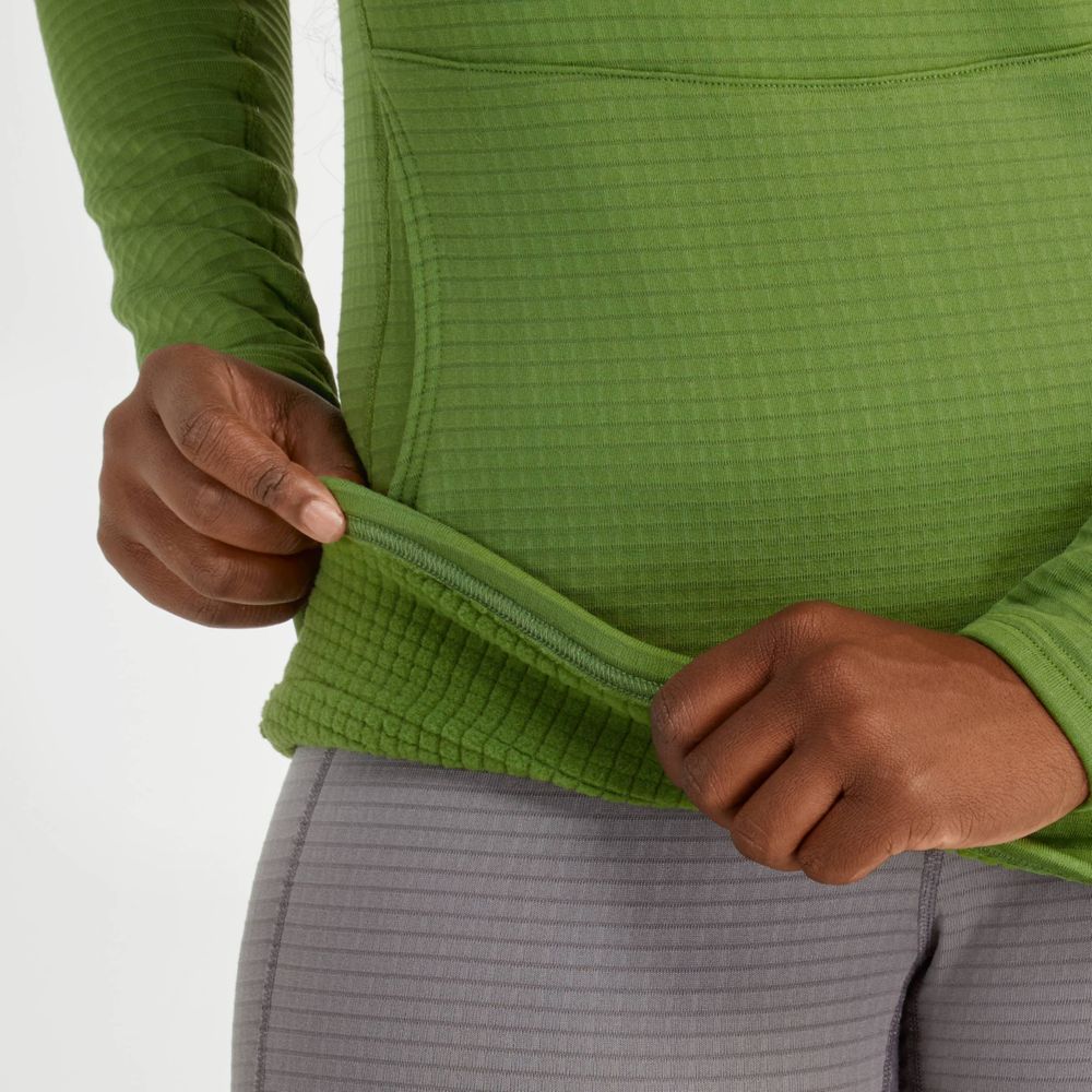 An individual in a green, textured NRS Lightweight Hoodie - Women's with long sleeves and UPF 50+ protection, paired with gray pants, pulls the hoodie's hem outward.