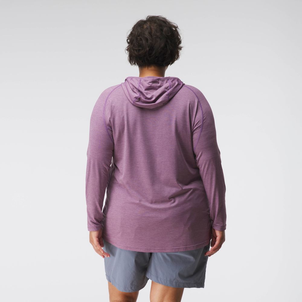 A woman in a purple NRS Silkweight Hoodie and gray shorts stands with her back to the camera against a plain background. The hoodie’s technical fabric provides excellent sun protection, maintaining comfort and style.