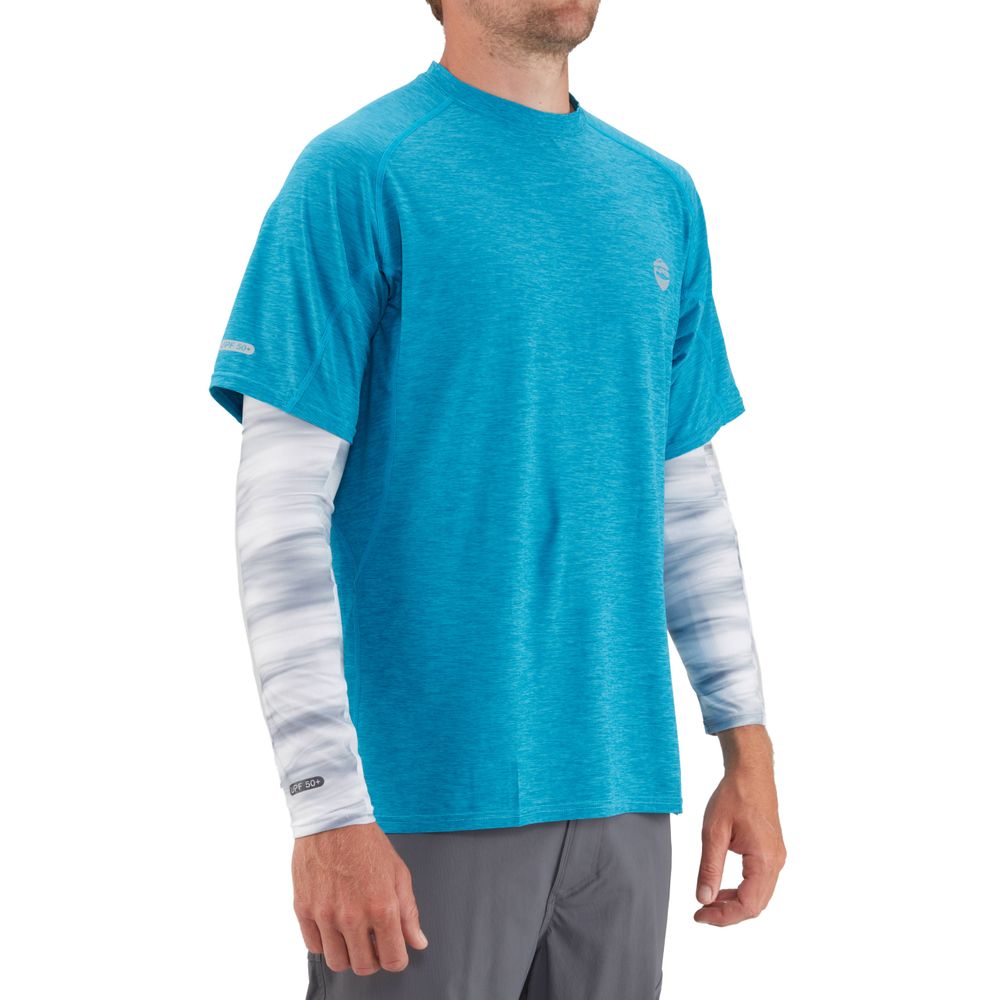 A man poses against a plain backdrop wearing a blue T-shirt over NRS H2Ozone Sun Sleeves, crafted from lightweight fabric, and gray pants.