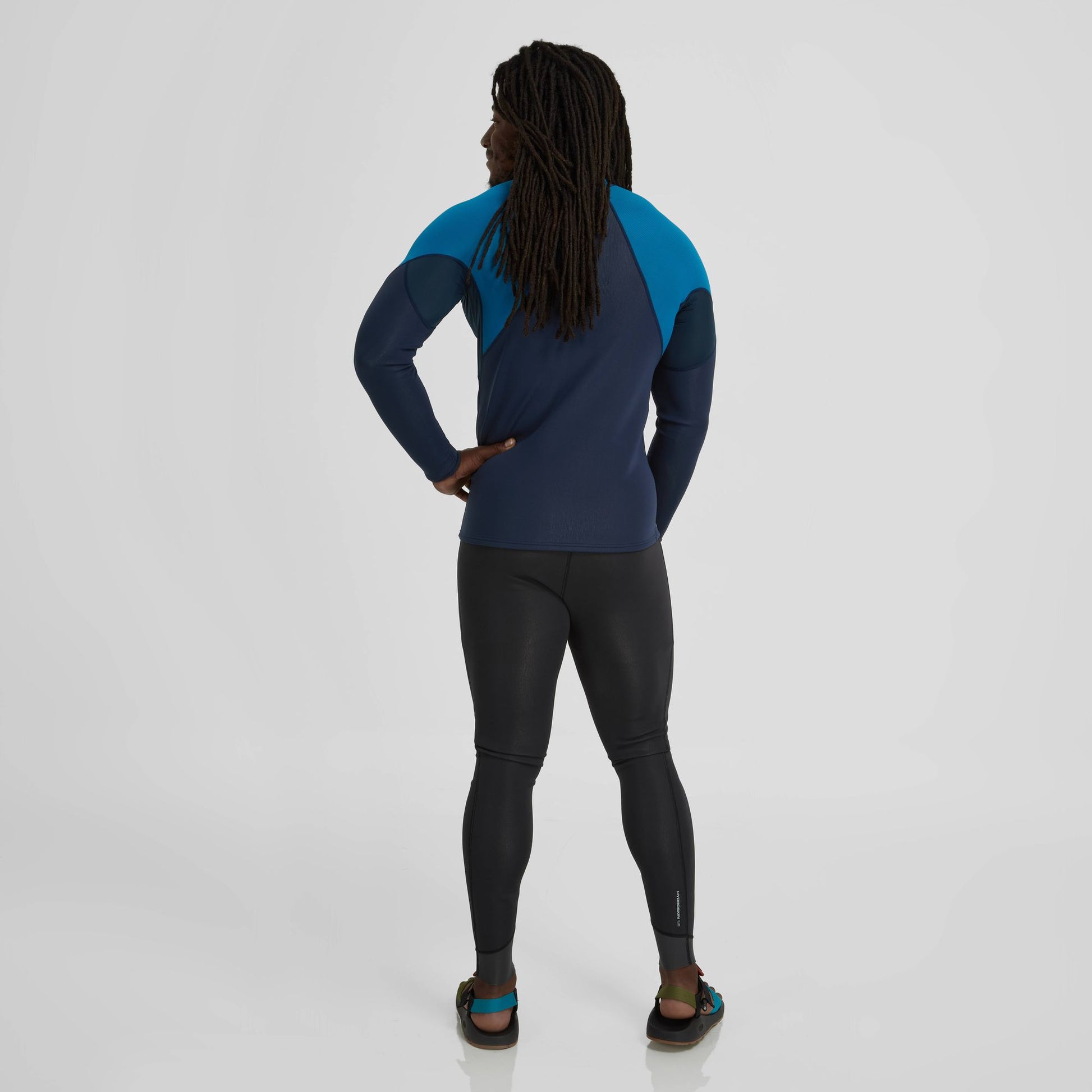 The back view of a man wearing a NRS Hydroskin 0.5 long sleeve shirt, an insulating top.