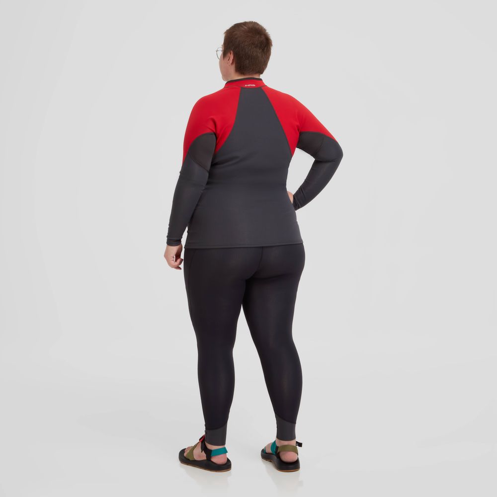 A woman in an NRS Hydroskin 0.5mm Pant and sandals faces away from the camera against a plain background, with the pants providing light insulation and enhancing her sleek silhouette.