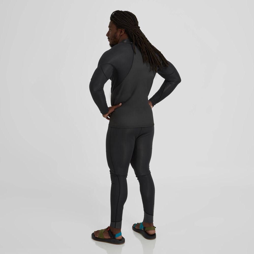 A person stands facing away, wearing an NRS Hydroskin 1.0mm Long Sleeve Shirt for men, reminiscent of neoprene, with colorful sandals providing a vivid contrast against the light background.