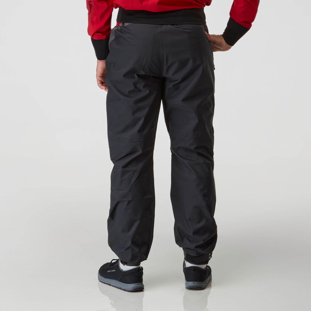 A person in a red jacket and NRS Endurance Splash Pant - Men's in black HyproTex fabric stands against a white background, facing away.