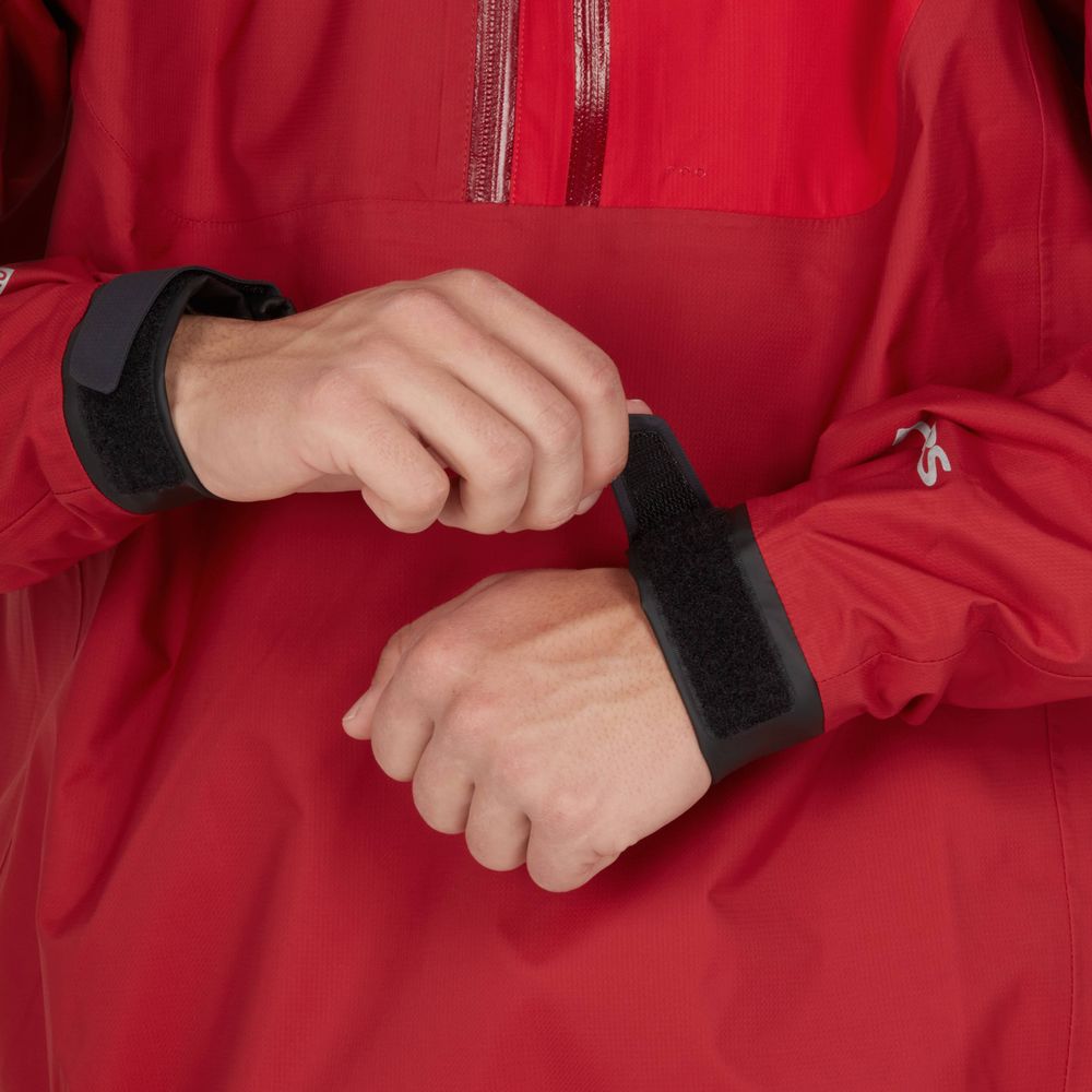 Someone adjusts the hook-and-loop fastener on the cuff of a red High Tide Jacket by NRS, designed for breathability.