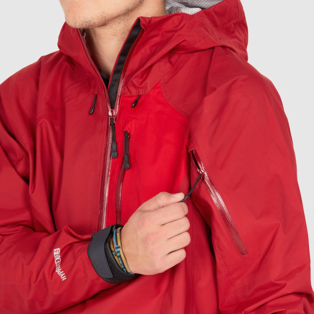 A person wearing the NRS High Tide Jacket - Men's, a red waterproof jacket, adjusts the zipper on the sleeve.