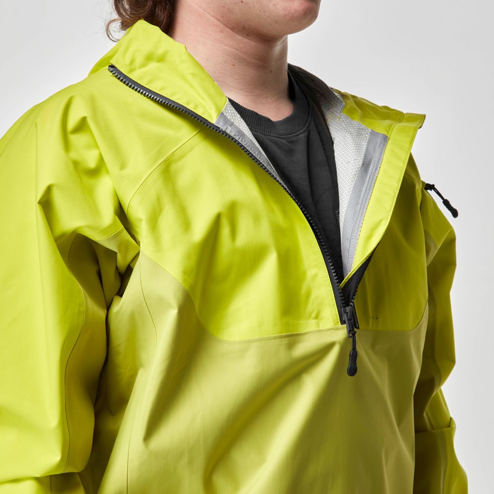 A person is wearing the NRS High Tide Jacket - Men's, a bright yellow breathable splash jacket with a half-zip, layered over a black shirt, facing right.