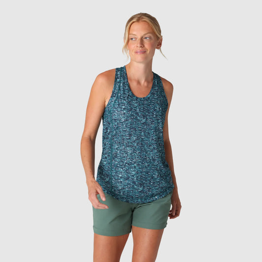 A woman wears the Outdoor Research Echo Tank W's in a blue pattern with green shorts against a plain light background—a true warm-weather essential.