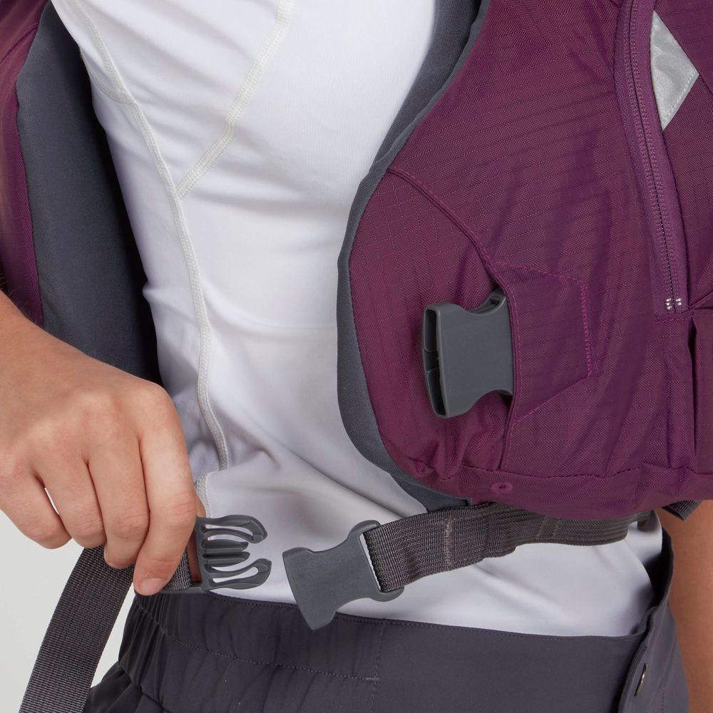 Someone fastening the waistband clip on a maroon NRS Ninja PFD vest over a white shirt and getting ready to wear the performance jacket for extra comfort.
