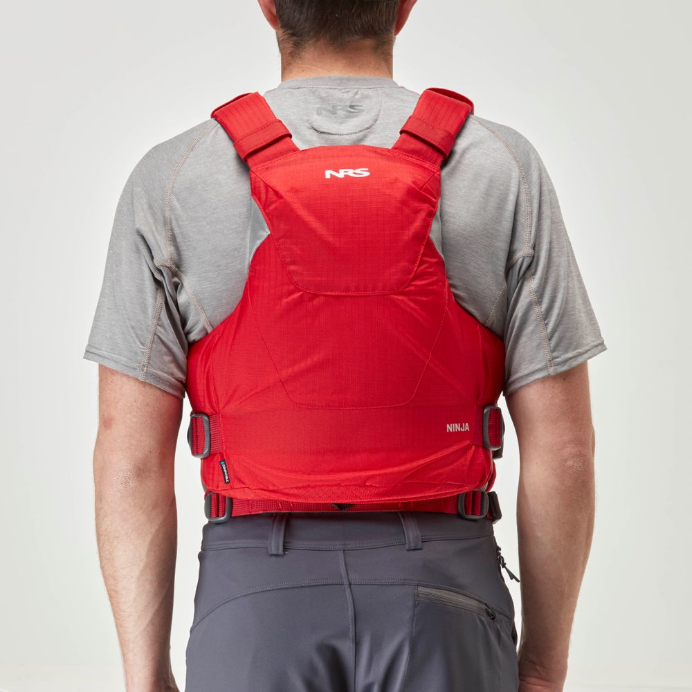 A person in a gray shirt and dark pants wears an NRS Ninja PFD with adjustable straps, seen from behind.
