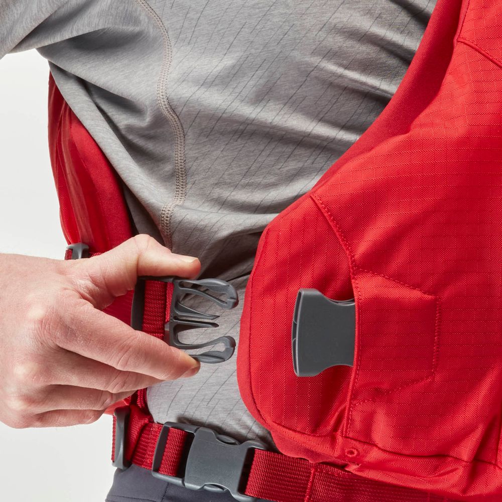 A person fastens a red harness with a gray clasp over a gray shirt, highlighting the precision of the NRS Ninja PFD's orbit fit system.