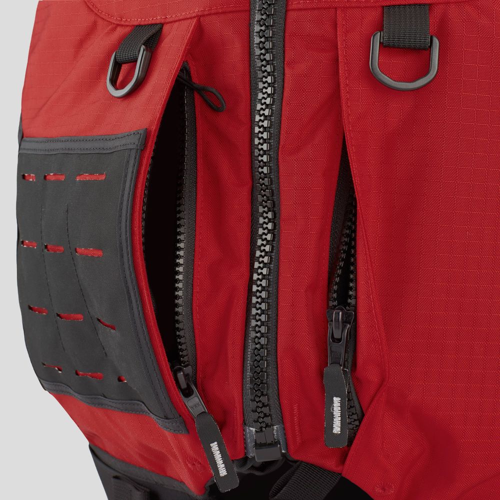 Close-up of the NRS Big Water Guide Hi-Float backpack in red, showcasing two open black zippers, buckles, and a textured black side patch. It includes reflective tape for visibility and customizable accessories for personalization.