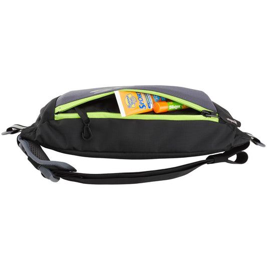 A black and gray sling bag is open, revealing a yellow packet and a small orange bottle inside, ideal for storing the NRS Zephyr Inflatable PFD.