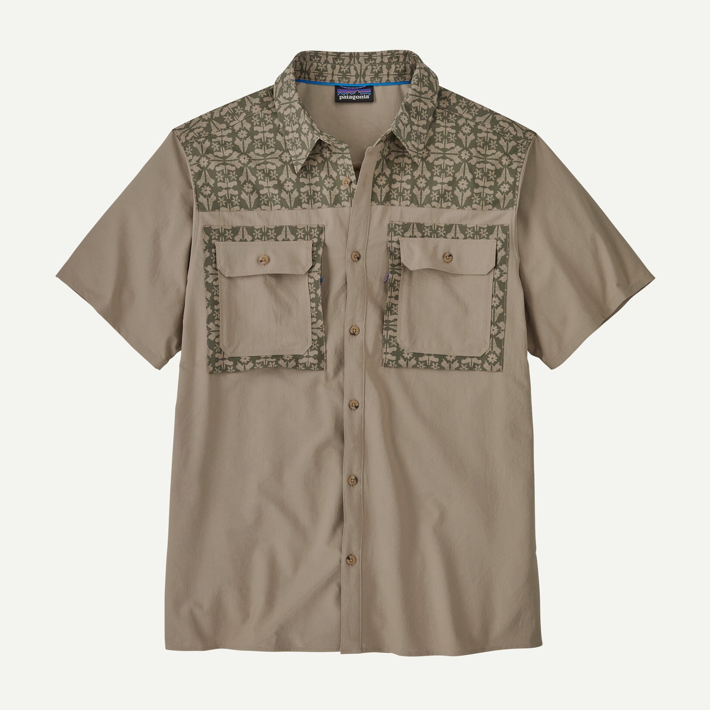 The Patagonia Self Guided Sun Shirt SS M's is a beige short-sleeve, collared button-up with decorative patterned panels on the shoulders and chest pockets, featuring five buttons down the front.