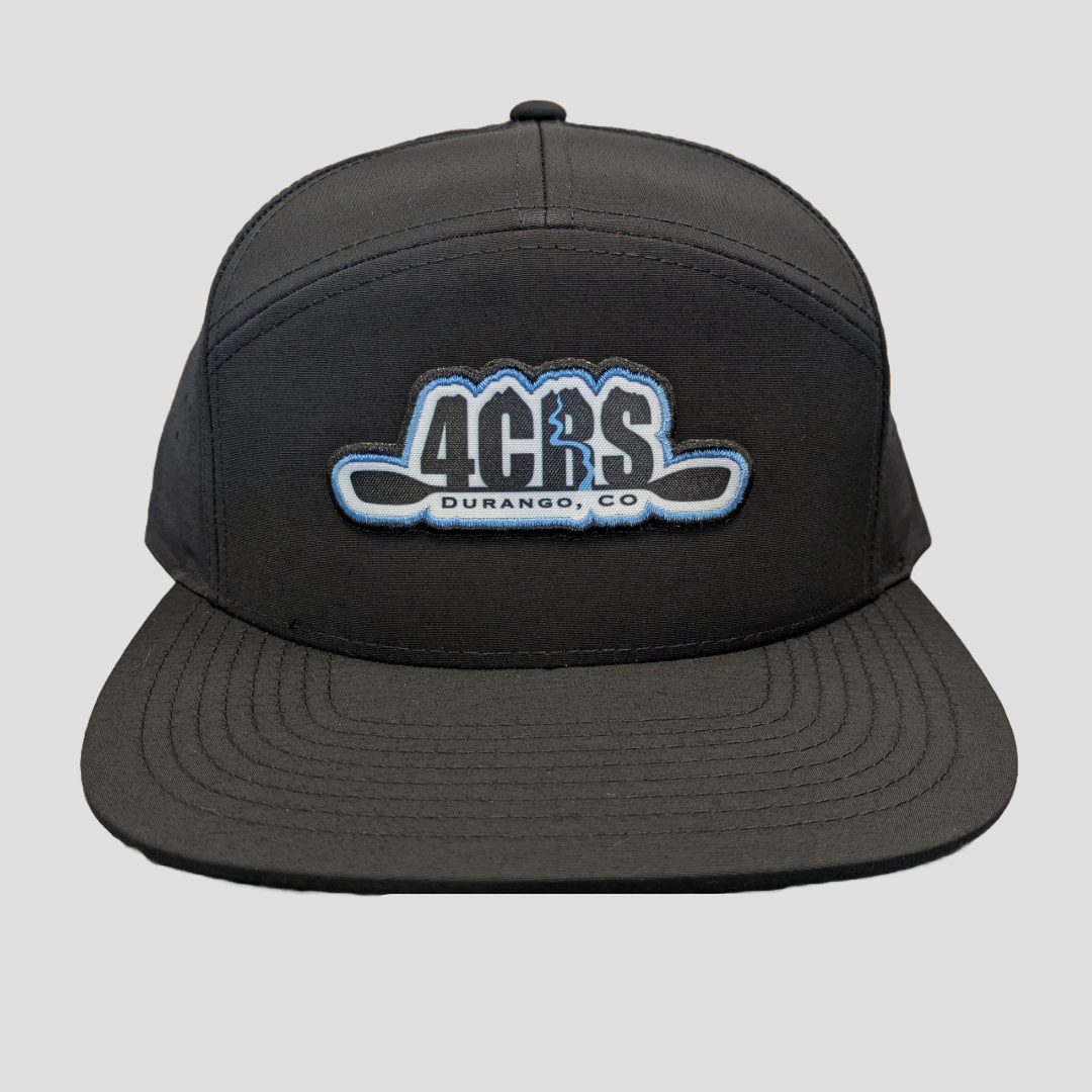 A black 4CRS 7 Panel Performance Hat by 4Corners Riversports, featuring a "4CRS Durango, CO" logo embroidered in blue and white on the front, is isolated on a light gray background.