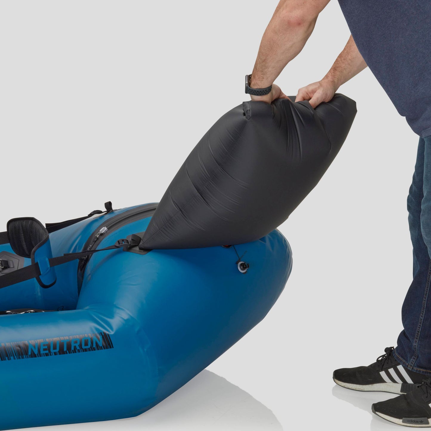 A person inflating a blue Neutron Packraft by NRS with a black air pump.
