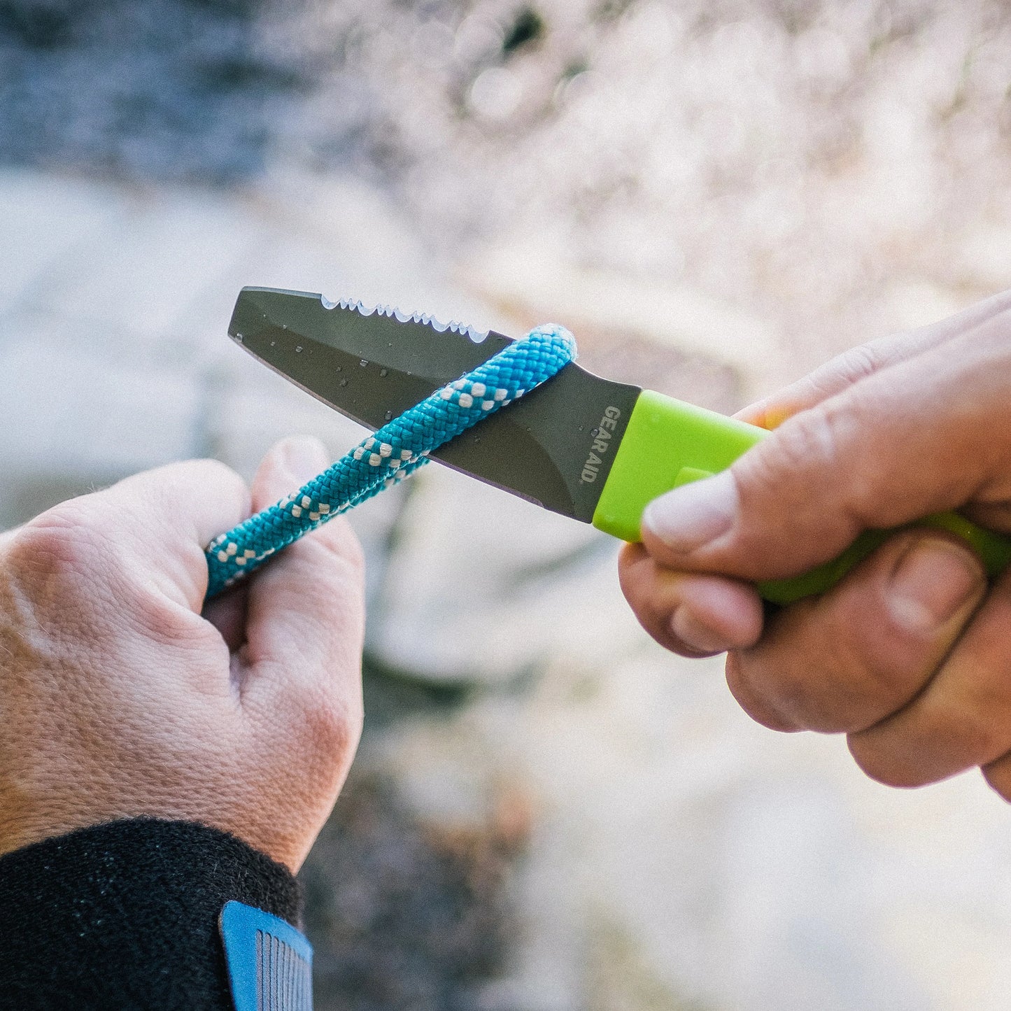 A person using an Akua Knife by Gear Aid to cut a rope.