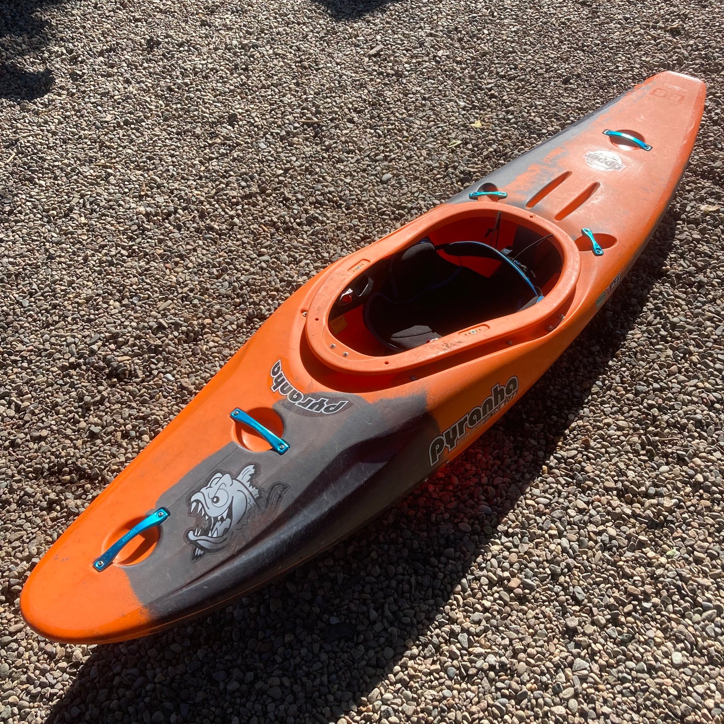 A Pyranha Demo Ripper 2.0 SM kayak laying on the ground.