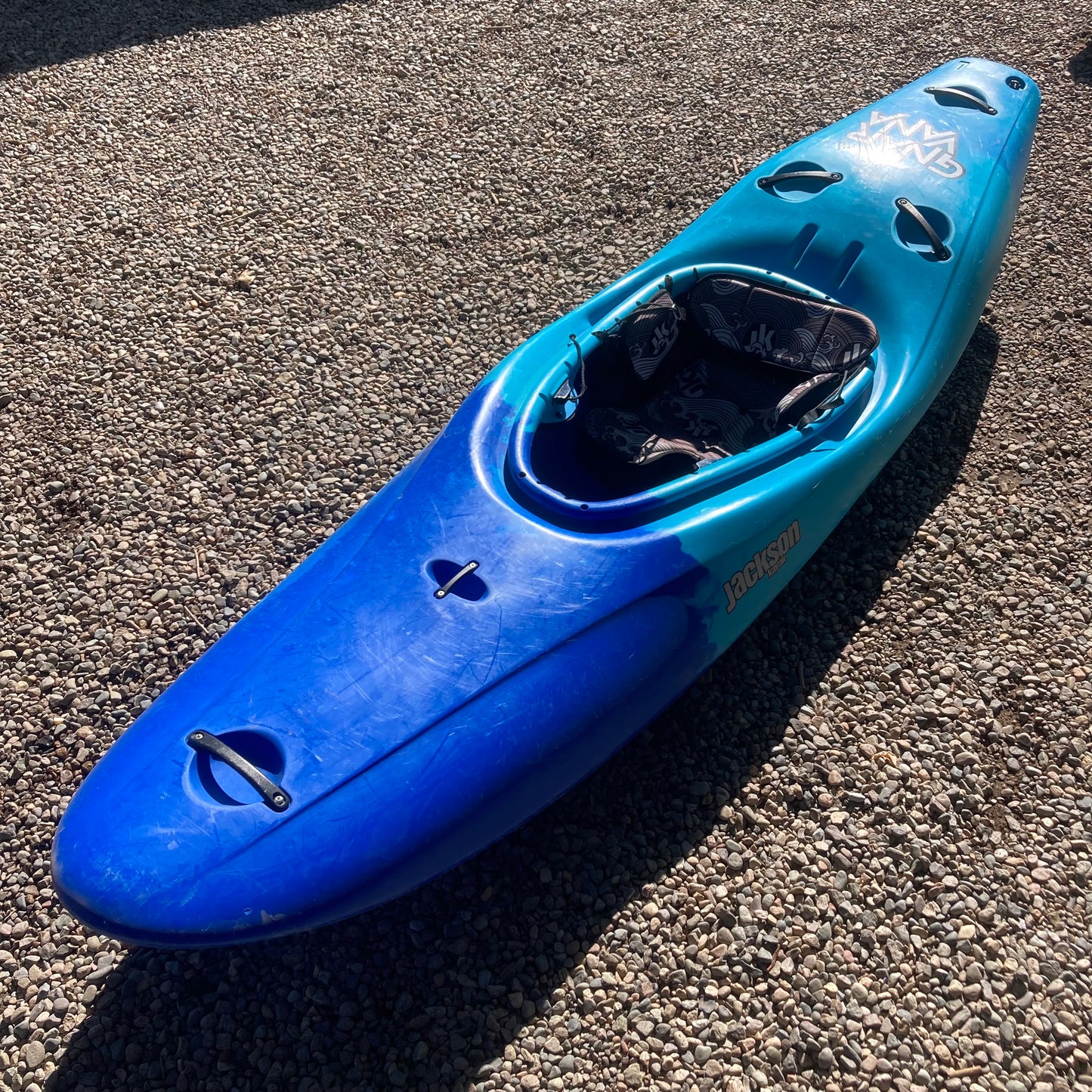 A Demo Gnarvana LG kayak by Jackson Kayak, sitting on a gravel driveway.