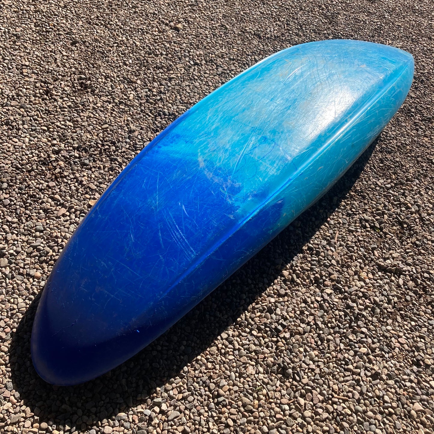 A blue and white Demo Gnarvana LG canoe laying on the ground, made by Jackson Kayak.