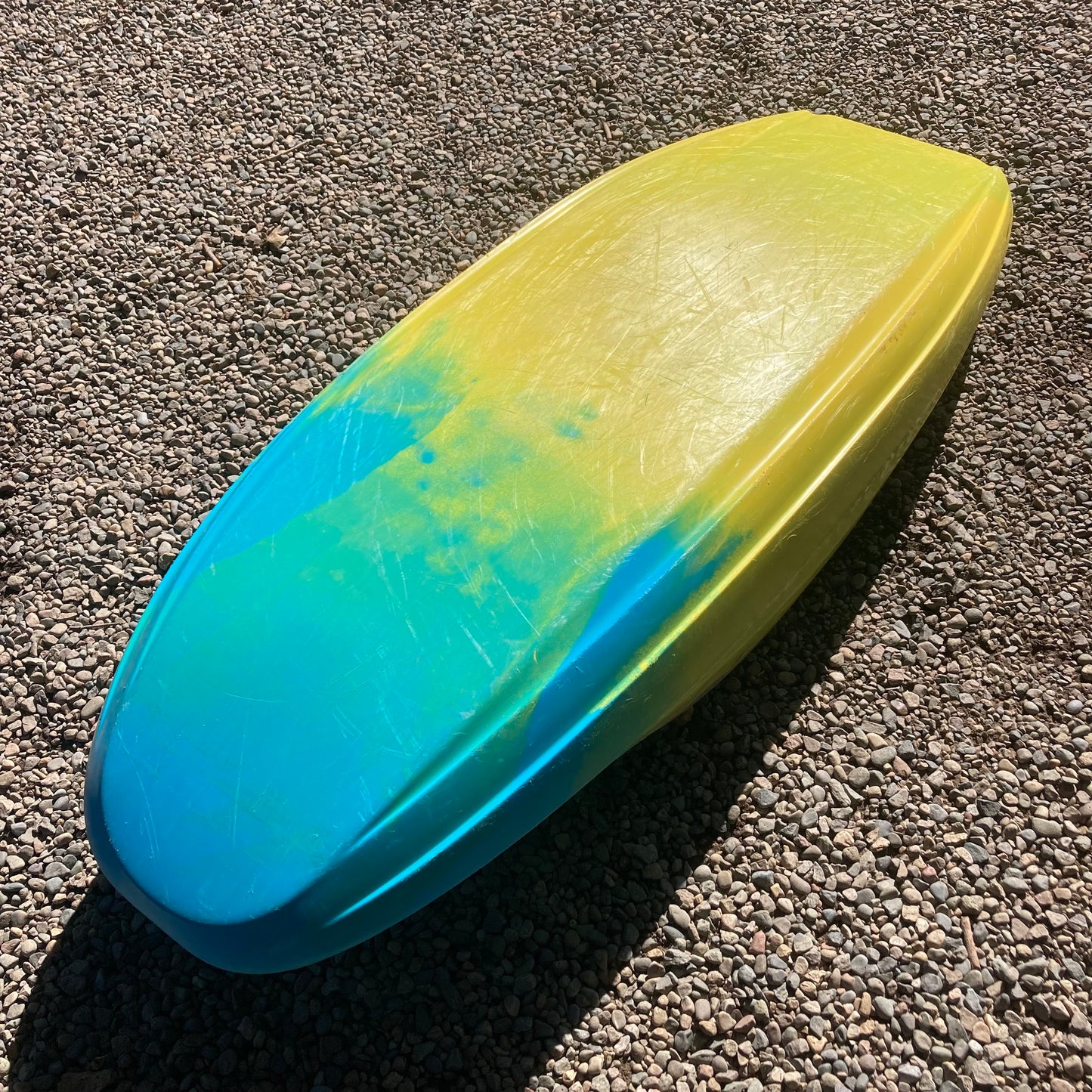 A yellow and blue Demo Rockstar V LG surfboard laying on the ground. (Brand: Jackson Kayak)