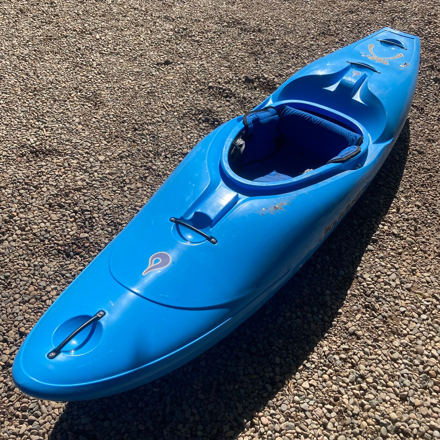 A LiquidLogic Demo RMX 96 kayak sitting on gravel.
