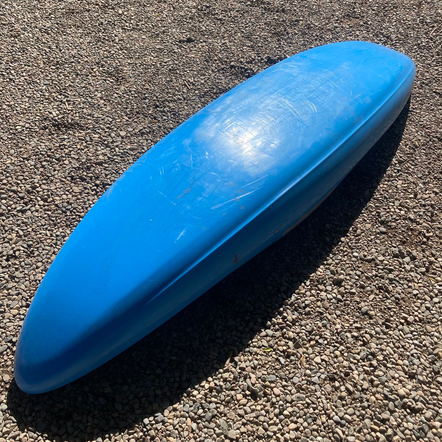 A LiquidLogic Demo RMX 96 canoe laying on a gravel road.