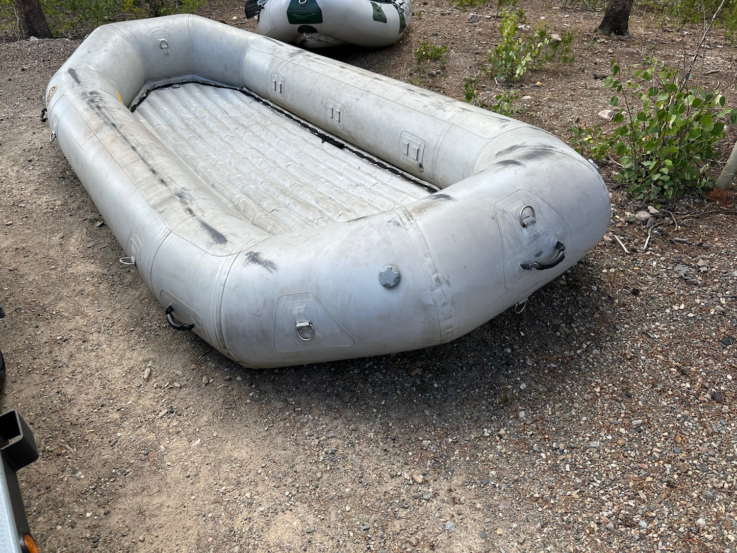 A fair condition 14' Rocky Mountain Raft, the 4Corners Riversports, sitting on a gravel road.