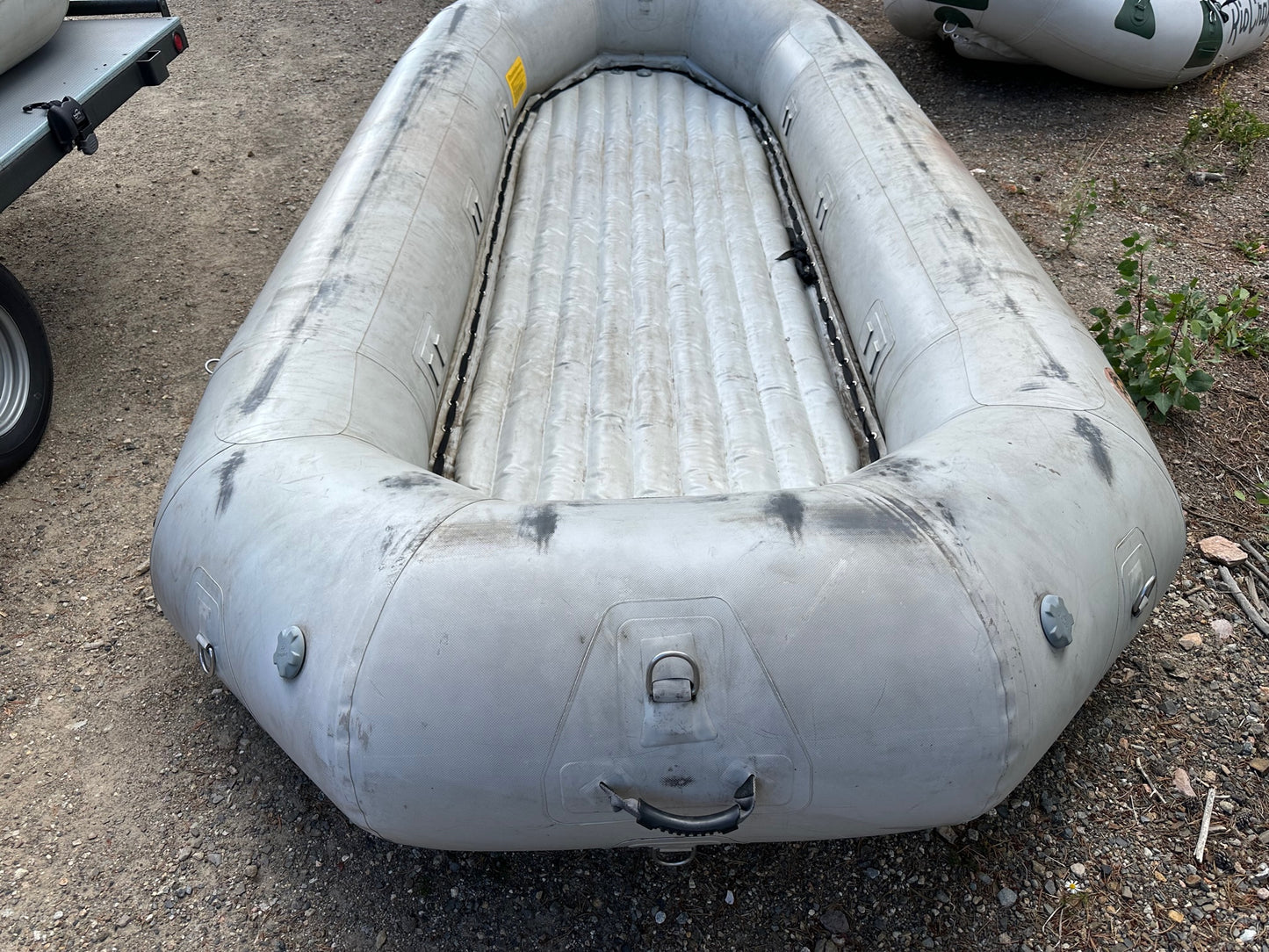 A fair condition Used 14' Rocky Mountain Raft from 4Corners Riversports sitting on a gravel lot.