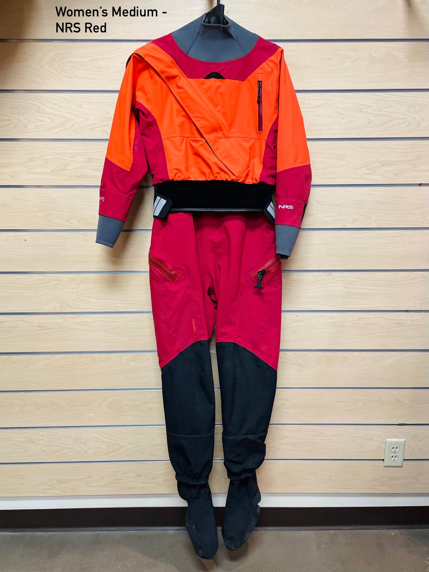 A 4Corners Riversports women's Rental Dry Suit hanging on a wall, available for shipping or rental.