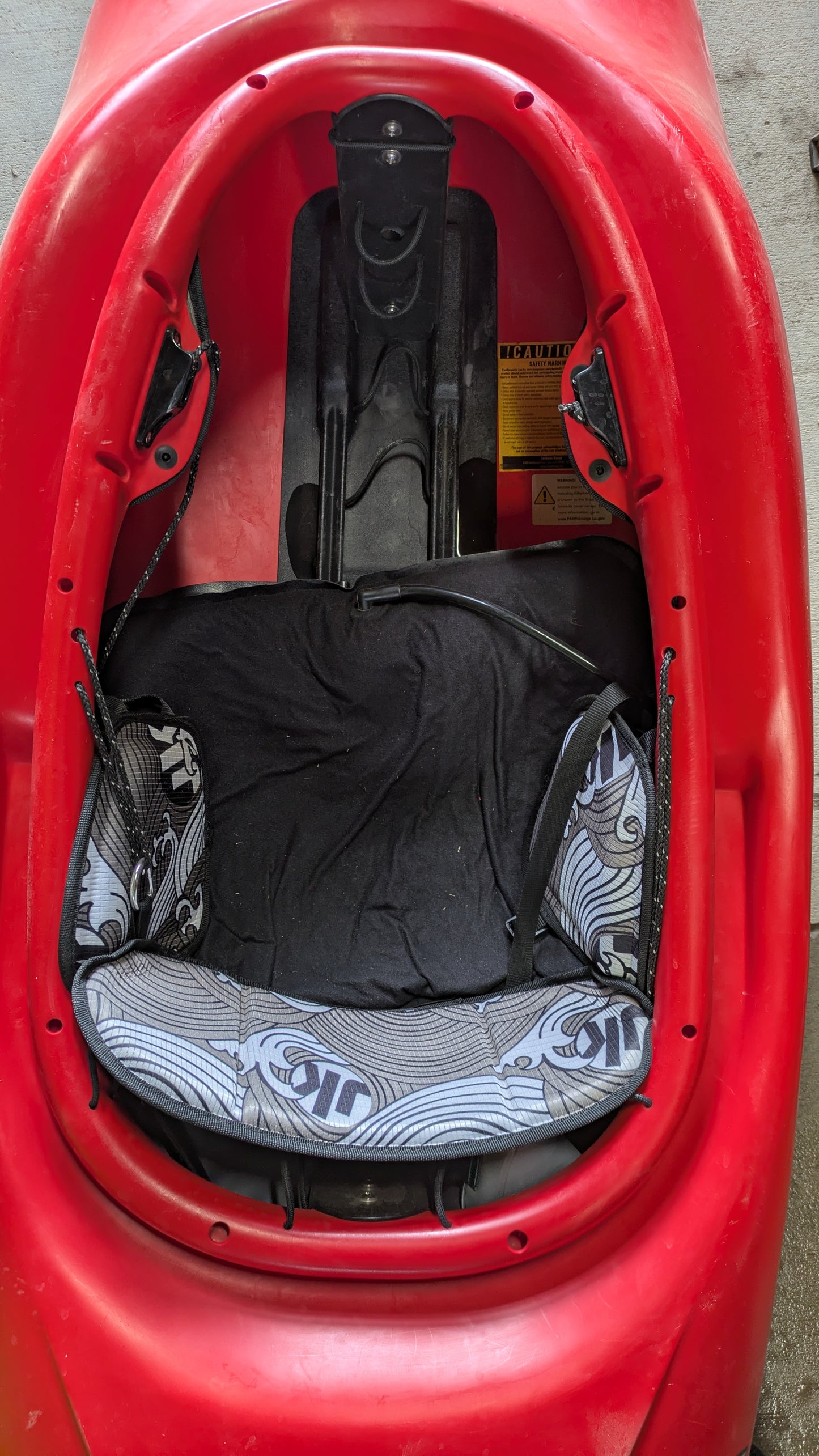 Top-down view of a Jackson Kayak Demo Rockstar V SM cockpit with cushioned seat, black and white patterned padding, and footrests—this used kayak combines comfort and control.