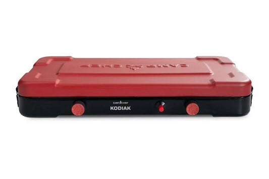 The Camp Chef Kodiak Camp Stove is a closed, rectangular portable stove with a red lid and two front control knobs, offering efficient outdoor cooking with up to 10,000 BTUs per burner.