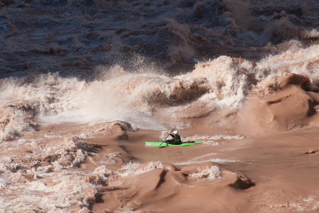 a person in a green kayak in a body of water.