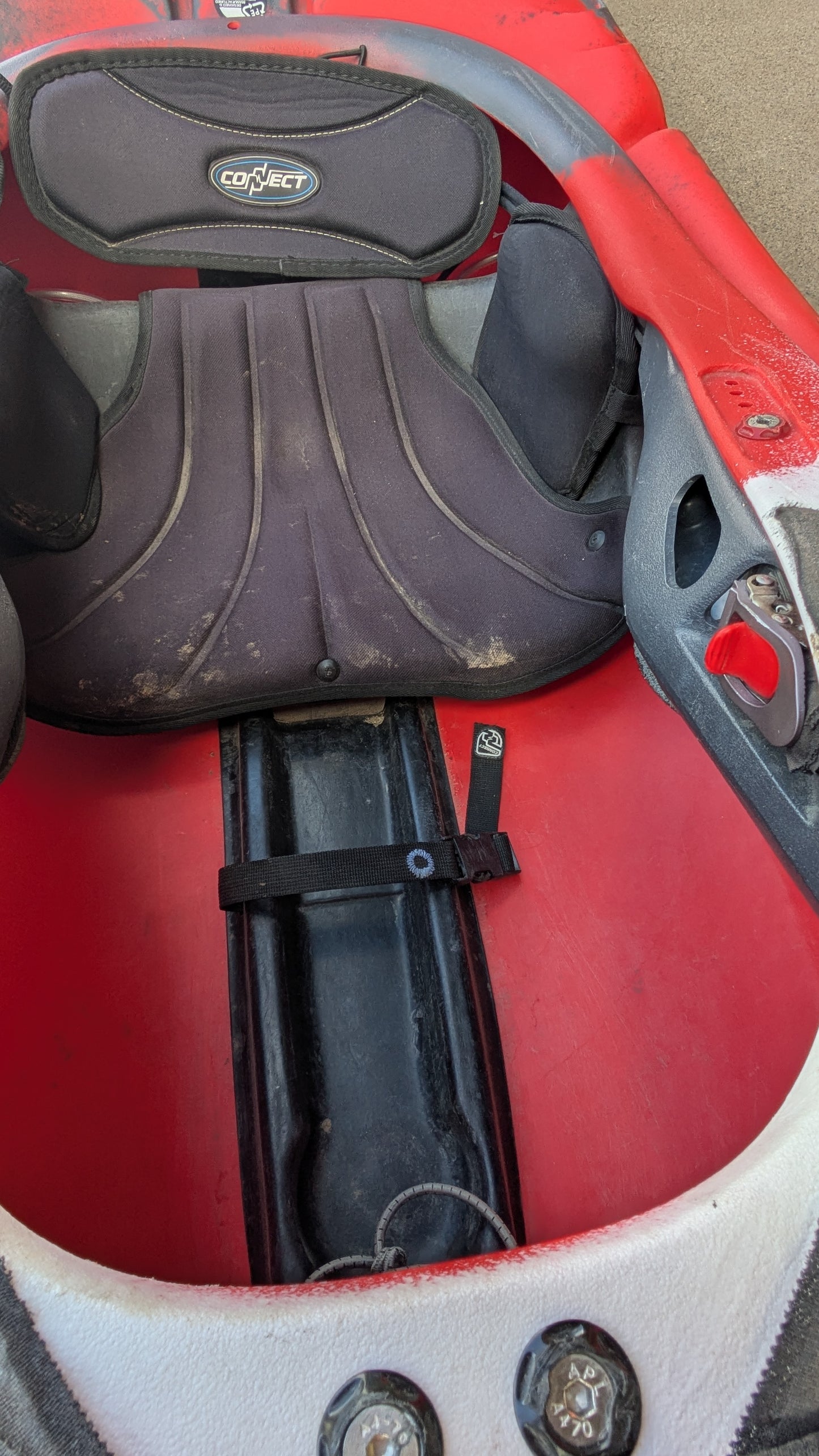 Close-up of the seat area inside a red Used Pyranha Machno kayak from 4Corners Riversports, highlighting the seat padding, "Connect" backrest, footrest, and internal fittings.