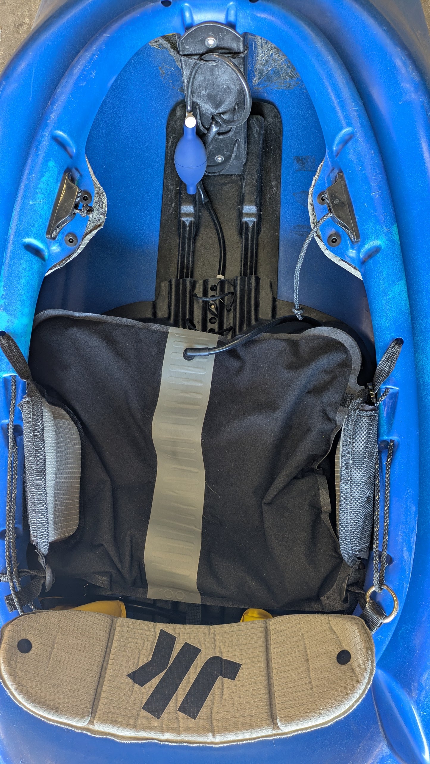 Top-down view of the Consignment Medium Jackson Rockstar 3.0 freestyle kayak cockpit at 4Corners Riversports, showing seat, footrests, and a hand bilge pump near the front—ideal details for anyone interested in a used kayak.