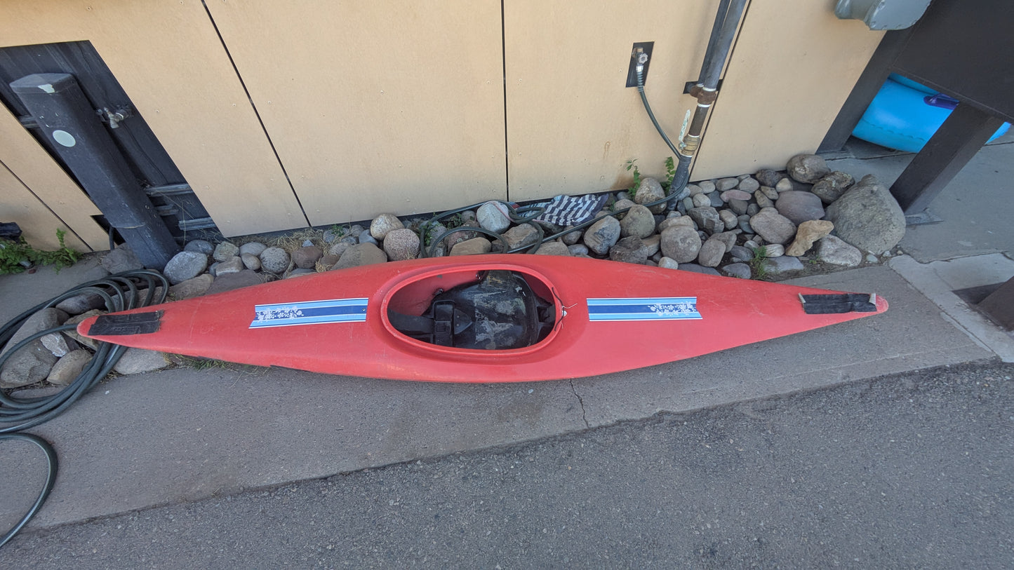 For sale: 4Corners Riversports Plastic Slalom Boat, red with two blue and white stickers. It’s upside down on concrete by a building wall, near rocks and a hose. Asking $50 OBO.