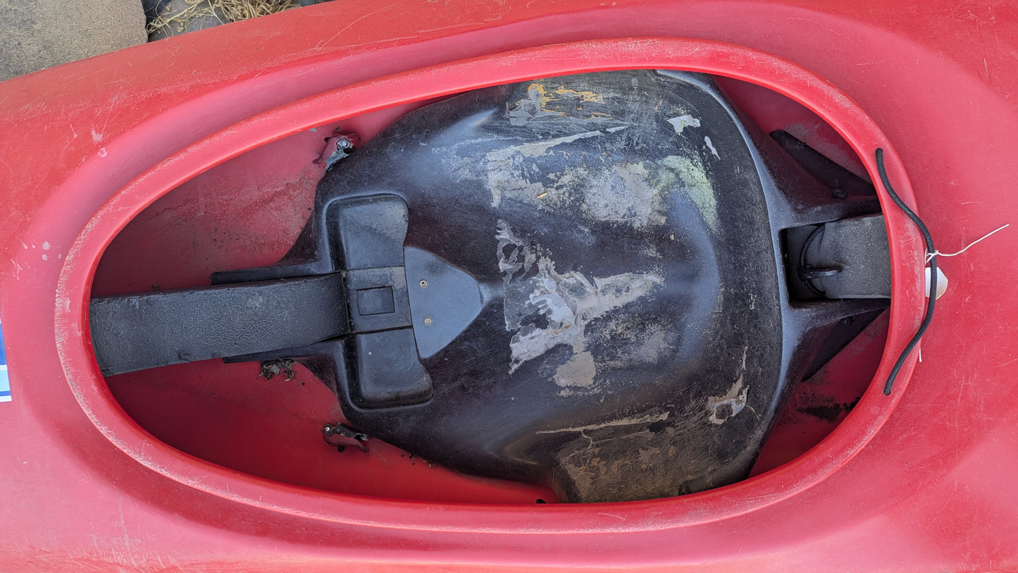 Close-up of the seat and interior of a red 4Corners Riversports Plastic Slalom Boat, showing a black seat pan, footrests, and worn areas on the seat. Priced at $50 OBO.