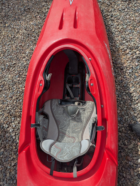Top-down view of an empty Consignment Dagger Axiom 9.0 kayak by Dagger, in red with a patterned gray seat, resting on gravel.