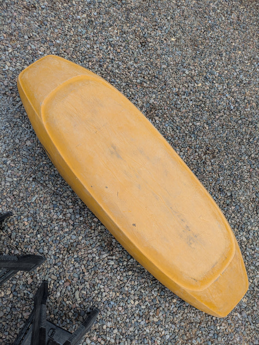 A yellow, rectangular seat cushion with rounded edges lies on gravel, evoking the comfort of a Wavesport Consignment LiquidLogic CR125 kayak.