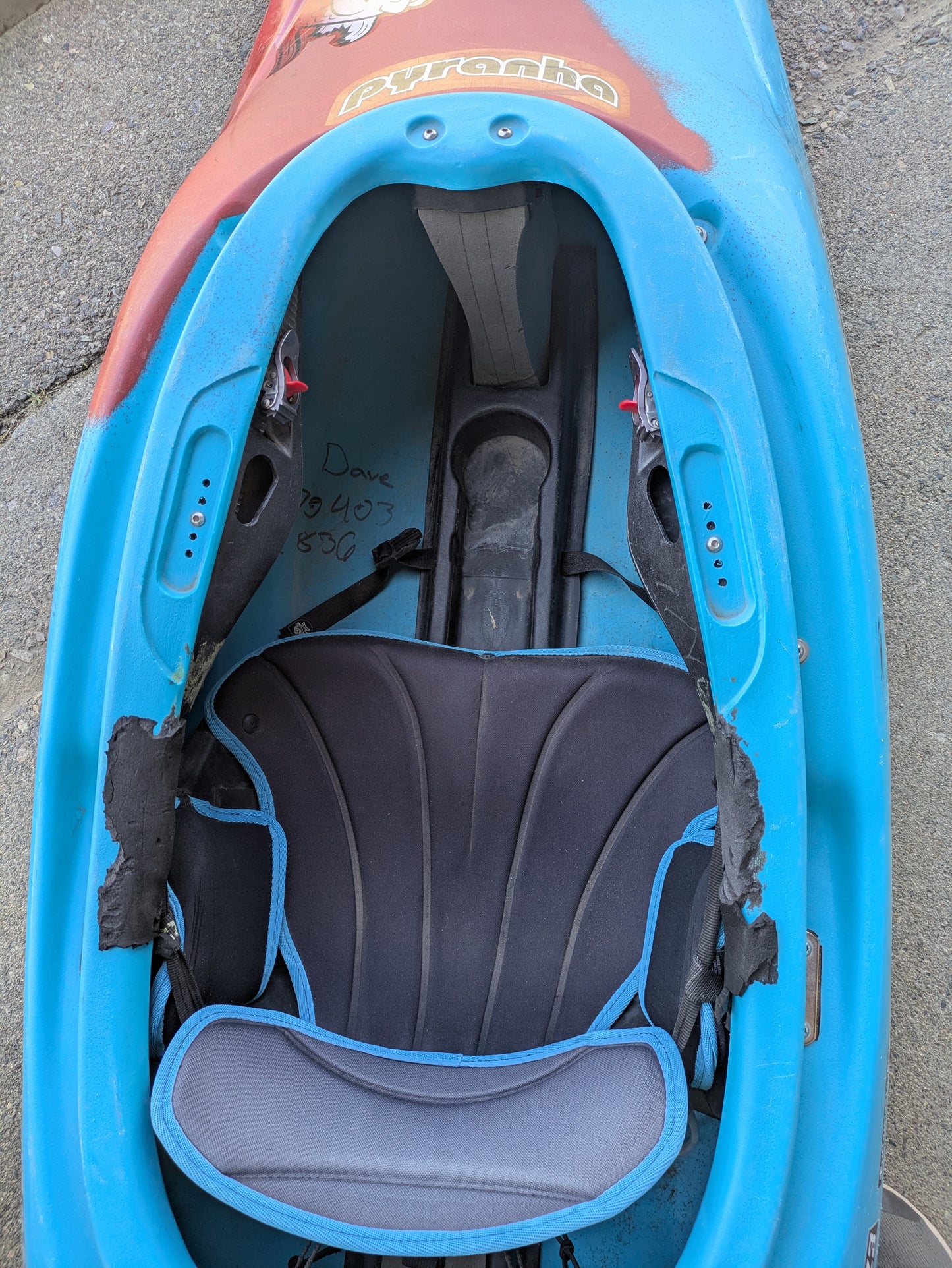 Top view of the 4Corners Riversports Consignment Medium Ozone downriver play kayak in blue and red, showing the cockpit with padded seat, footrests, and handwritten notes on the interior wall.