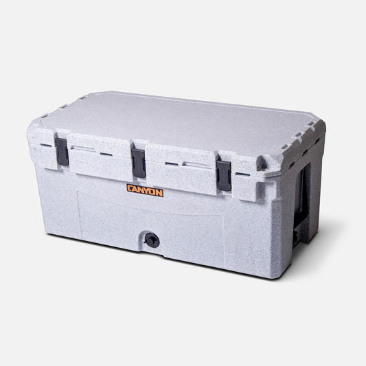 The Canyon Coolers Prospector 125 Raft Cooler is a large, rectangular gray cooler with black latches and handles—ideal for keeping supplies cold on any adventure.