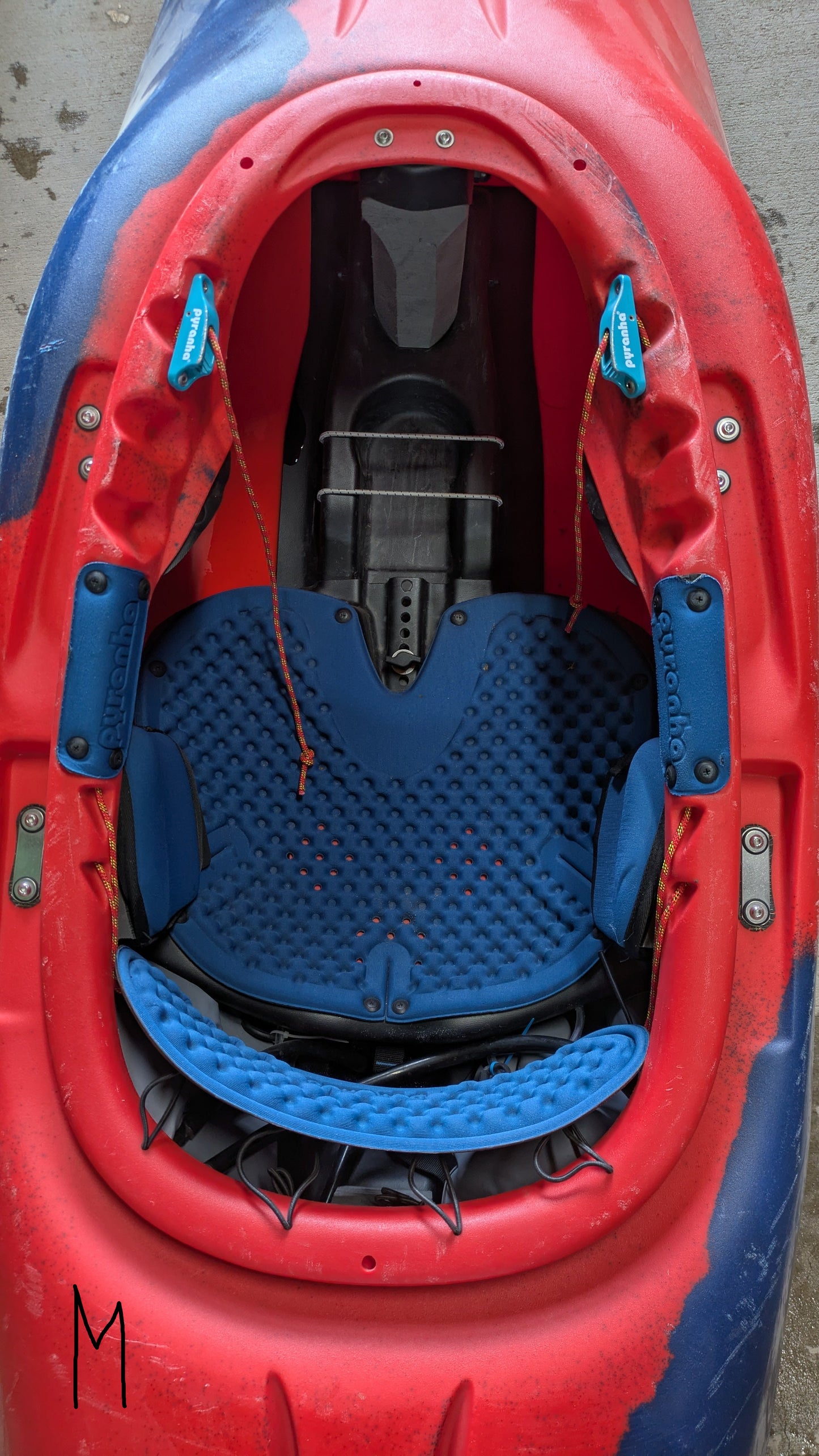 Top view of a Pyranha Demo Helectron cockpit with blue padded seat and adjustable footrests, photographed on concrete. Perfect choice for anyone after a premium used kayak from our demo fleet.