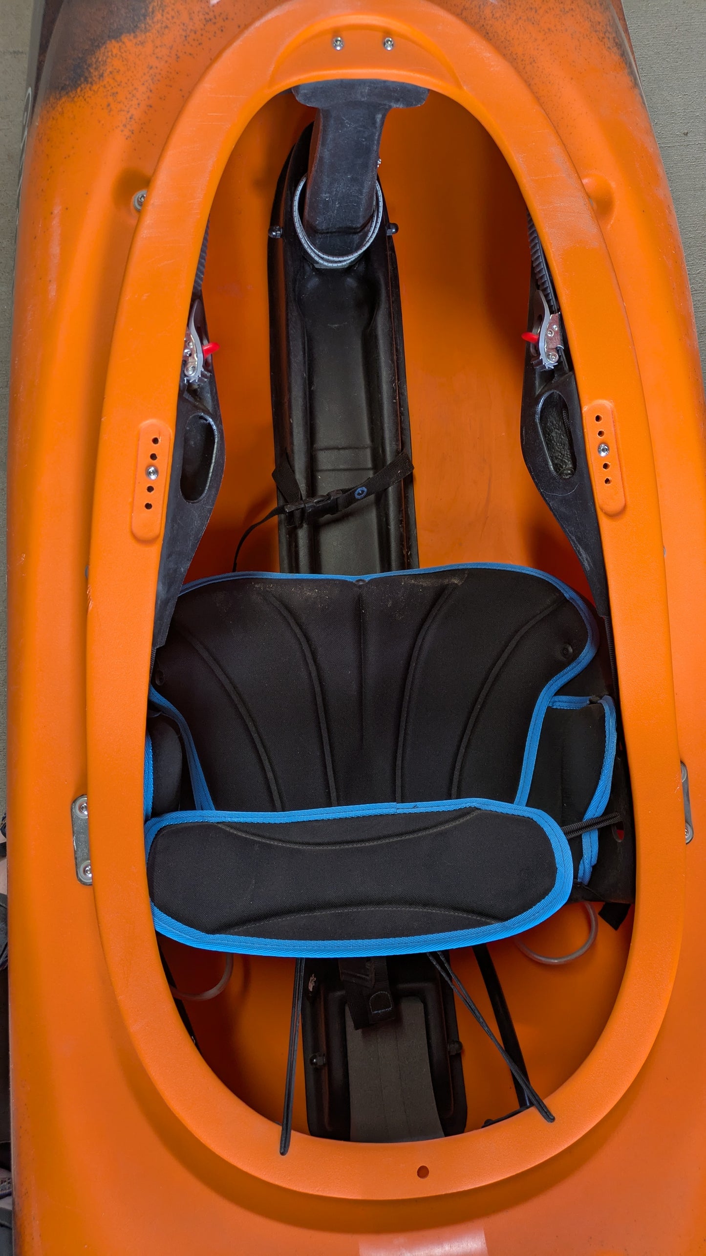 Top-down view of the cockpit of the Pyranha Demo Scorch LG kayak, highlighting the seat cushion with blue trim and footrests inside.